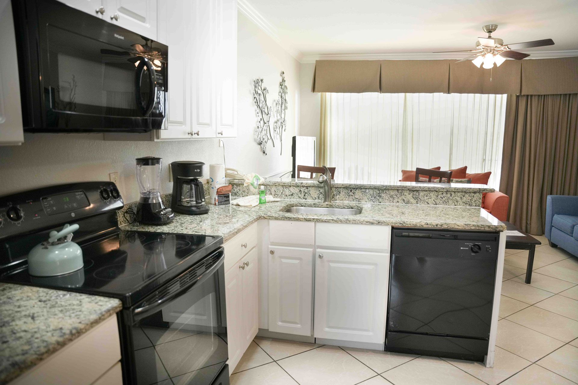 A kitchen with granite countertops, black appliances, and white cabinets.